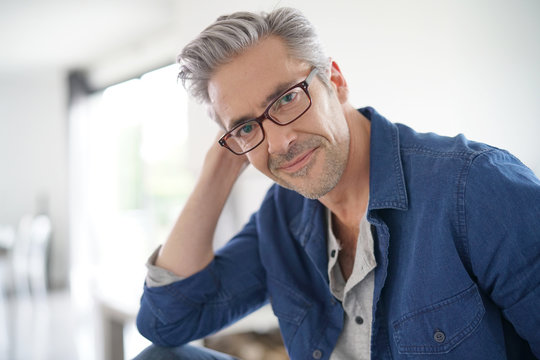 Portrait of mature man with eyeglasses sitting on sofa