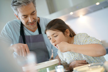 Daddy with daughter baking cake together in home kitchen
