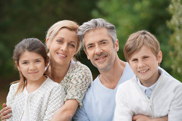 Portrait of happy family of four standing outside