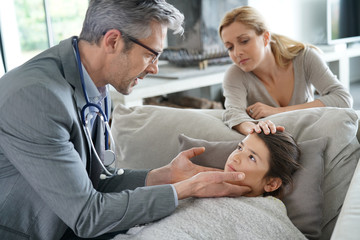 Fototapeta na wymiar Doctor visiting sick little girl at her house