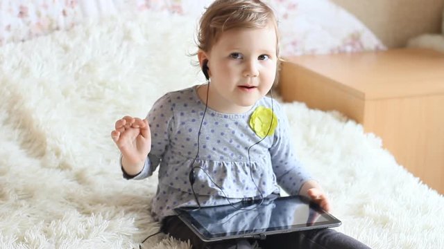 Funny happy child with tablet in hands dresses headphones