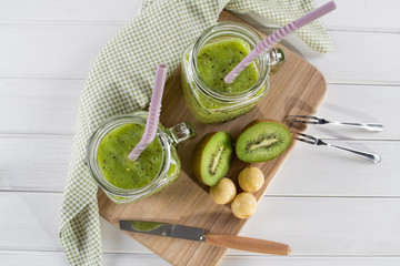 Fresh and healthy green Juice smoothie with kiwi and banana in glass jar. On white background . Top view