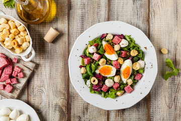 Delicious Italian salad with salami, egg, crostini and mozzarella.