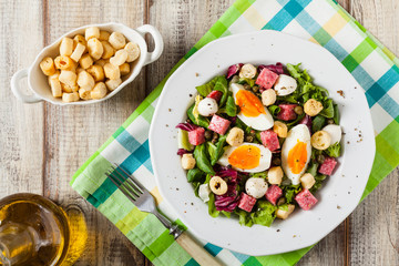 Delicious Italian salad with salami, egg, crostini and mozzarella.