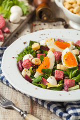 Delicious Italian salad with salami, egg, crostini and mozzarella.