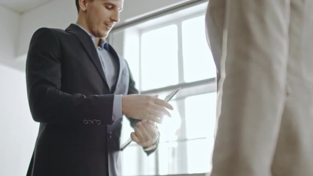  Unrecognizable businessman shaking hands with business partner after making deal, then showing contract 