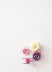 Colored thread coils on white background, sewing tools