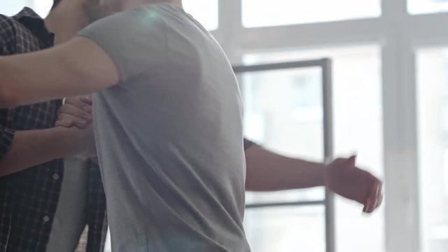 PAN with mid-section of good friends casually pound hugging each other and then chatting about life 