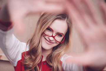 Stylish hipster woman with red eyeglasses making focus framing gesture