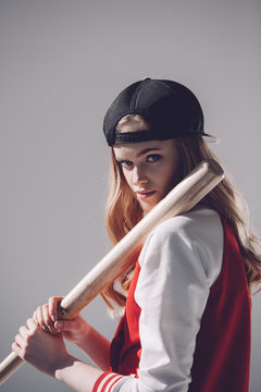 Attractive Young Woman In Cap Holding Baseball Bat And Looking At Camera