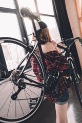Fototapeta na wymiar back view of stylish woman holding sports bicycle
