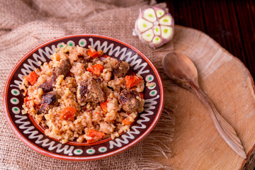 Pilaf on the brown plate on a wooden background. Top view. Copy space. Rustic style
