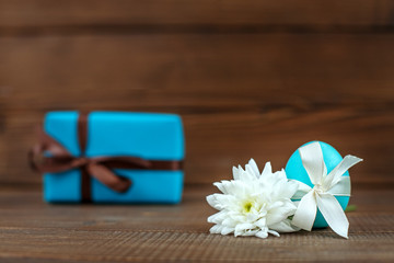 Light blue Easter egg and gift on a wooden background. Place for inscription. Concept Happy Easter.