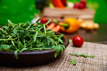 Arugula leaves in bowl. Fresh salad. Natural raw vegetables. Organic bio food on rustic wooden table.
