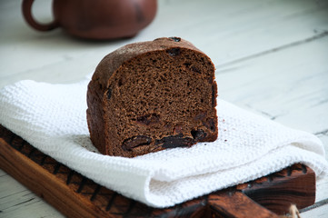 Cut of rye bread with dry fruits filling on a wooden board with white towel. White background.