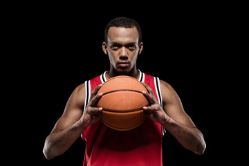 African american basketball player posing with ball on black