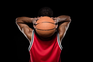 Back view of african american basketball player throwing ball on black