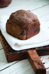 Rye bread with dry fruits filling on a wooden board with white towel. White background.