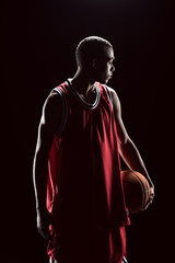 African american basketball player posing with ball on black