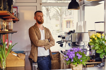 A man in a small cafe with a lot of flowers and coffee machine.