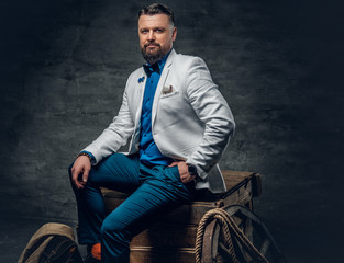 Obraz premium A man dressed in a white jacket and bow tie sits on a wooden.