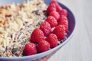 Raspberry, nuts and sunflower seed in a cup on a wooden desk.