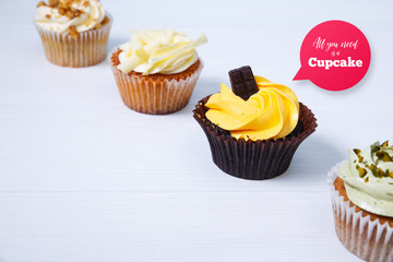 Cupcakes with buttercream. Sweet cake with pistachio cream and small chocolate bar. Dessert on white wooden background.