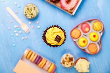 Cupcake with chocolate bar, Donuts and Macaroons. Sweet dessert. Cakes with buttercream. Almond macaron cookies. Delivery box.