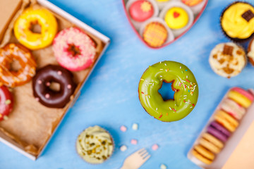 Pistachio glazed donut, cupcakes and macaroons. Sweet dessert. Cakes with buttercream. Almond macaron cookies. Delivery box.