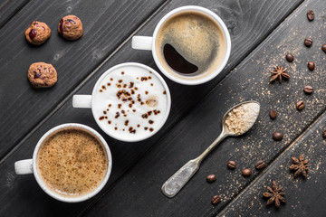 top view of cups of coffee, coffee beans, cookies and spices on table
