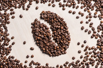 Close-up top view of coffee bean symbol made from roasted coffee grains on table