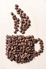 Close-up top view of coffee cup symbol made from roasted coffee beans on table