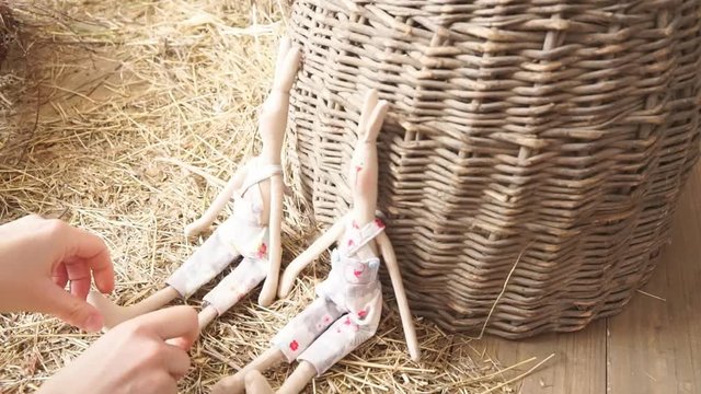 Female hand puts doll tilde have a wicker basket for the photo shoot