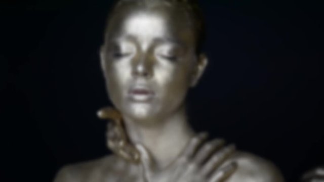 Girl painted silver. 6 hands on your face: see no evil,hear no evil, speak no evil. The image is blurred and out of focus . The mystical effect.