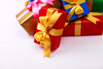 Gift boxes with bow. Colored presents wrapped with paper and ribbons. Christmas or birthday packages. Celebration design. On white table.