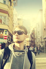 Handsome traveler with sunglasses on street. Urban Traveler Vacation Concept. Toned.