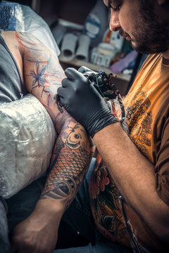 Professional tattooer works in tattoo studio