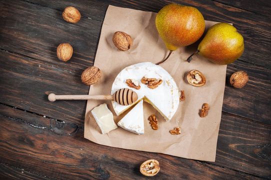 Camembert cheese with walnuts, honey and pears on rustic table