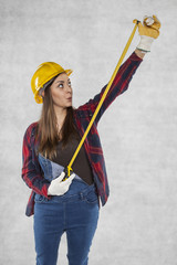 Woman builder stretches a meter, surprised face