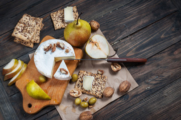 Camembert cheese with walnuts, honey and pears on rustic table