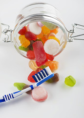 Glass jar full of goodies next to a toothbrush. Isolated. Vertical shoot.