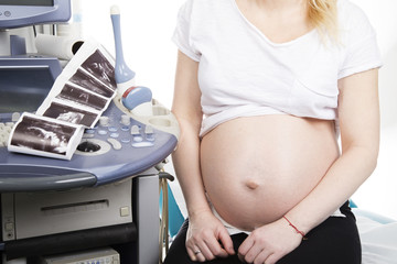 Kobieta w ciąży siedzi w gabinecie ginekologicznym 