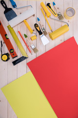 Top view of set of construction tools and colored paper on wooden table