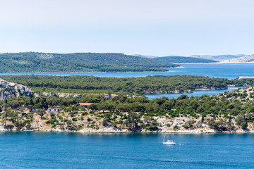 Fototapeta premium Mediterranean landscape of adriatic coast. Ship in the sea bay and rocks on foresgound and green mountains on background.