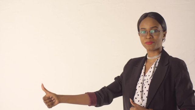 Joyful black woman stands before white wall and tells something