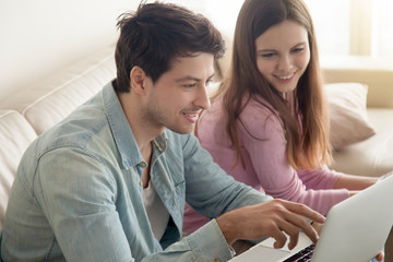 Young man and woman sitting and talking, man using laptop computer. Browsing internet, downloading apps, social networking, online shopping, banking, planning, self-employed freelancers