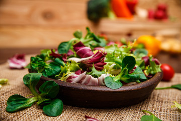 Provence mix salad. Leaves of endive or chicory, lamb and rose salad. Raw vegetables. On wooden table.