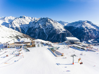 Ski resort in the Alps with ski lift and people skiing on the slope