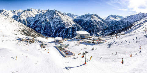 Panoramic aerial view of ski resort in the Alps with ski lift and people skiing on the slope