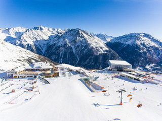 Ski resort in the Alps with ski lift and people skiing on the slope